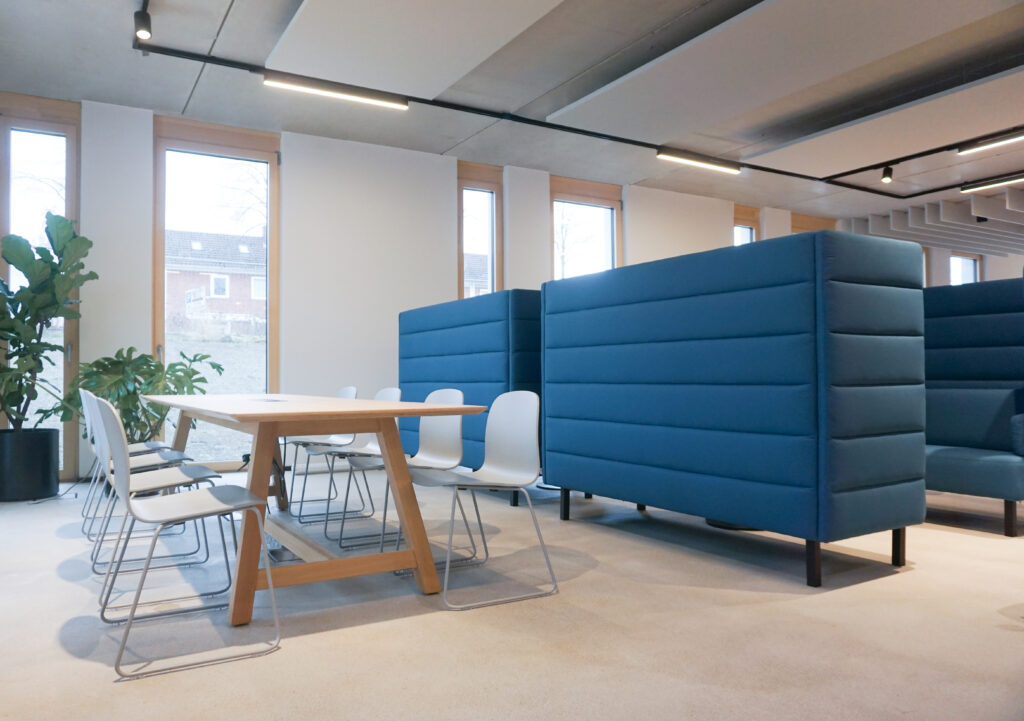 Holztisch mit Stühlen und blaue Sofas als Raumtrennung