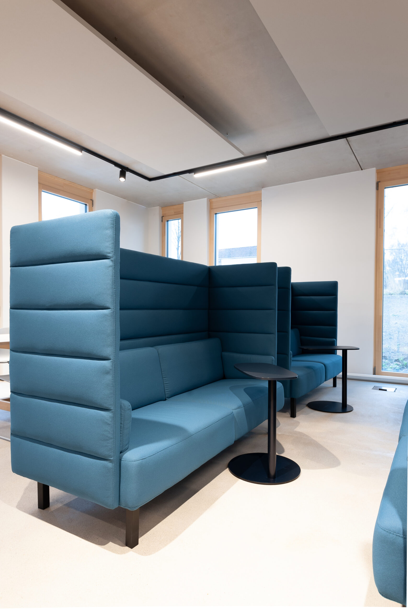 blaues Sofa mit hohem Rücken und Beistelltischen