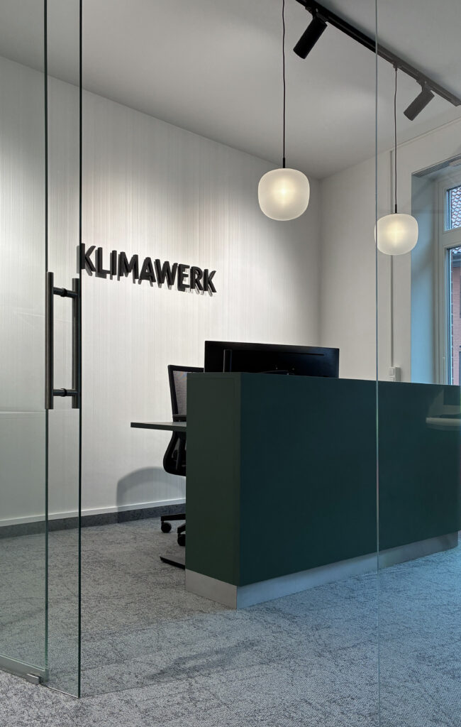 grüner Empfangstresen mit runden Pendelleuchten und Logo