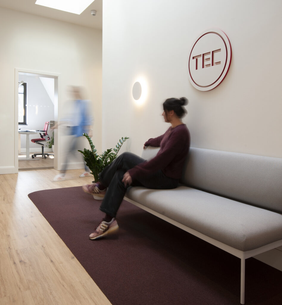Flur mit grauem Sofa auf rotem Teppich und einem runden Logo auf der Wand