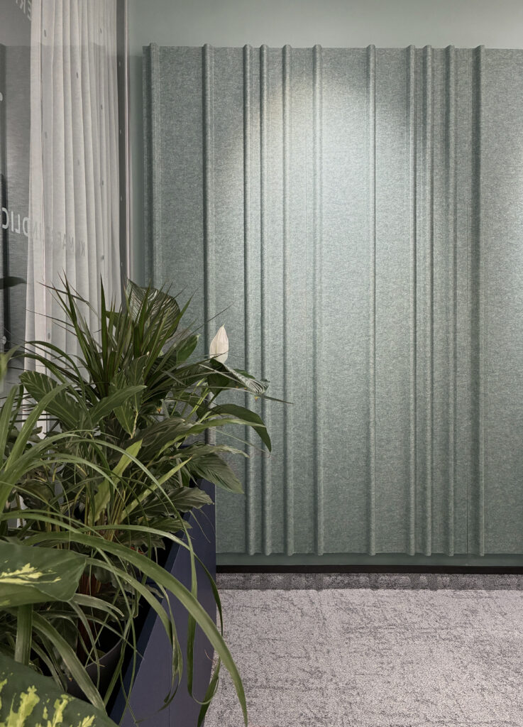 Raumakustische Wandverkleidung in Grün mit Pflanzenkästen